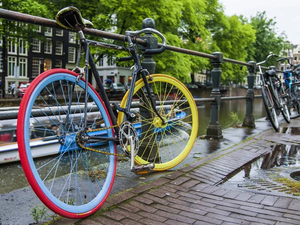 Amsterdam, Netherlands, on July 10, 2014. Bicycles are parked on the city street on the bank of the channel — Stock Photo, Image