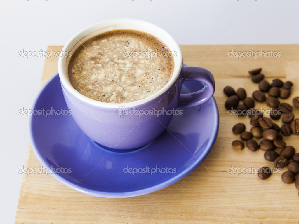 Cup of black coffee with cream and grains of the fried coffee