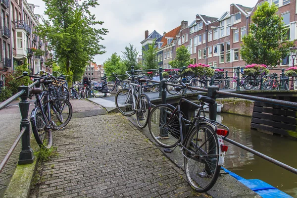 Amsterdam, Netherlands, on July 10, 2014. Bicycles are parked on the city street on the bank of the channel — Stock Photo, Image