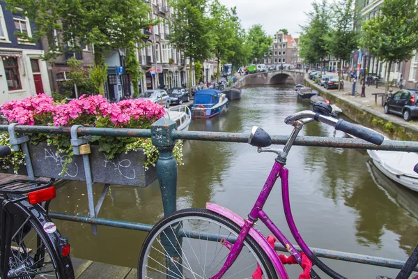 Amsterdam, Netherlands, on July 10, 2014. Bicycles are parked on the city street on the bank of the channel — Stock Photo, Image