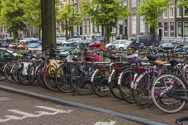 Amsterdam, Netherlands, on July 10, 2014. Bicycles are parked on the city street on the bank of the channel — Stock Photo, Image