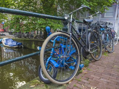 Amsterdam, Hollanda, üzerinde 10 Temmuz 2014. Bisiklet kanal kıyısında şehrin cadde üzerinde park edilmiş