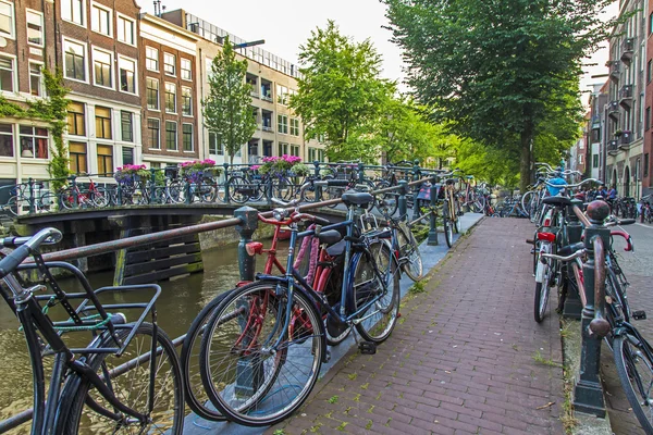 Ámsterdam, Países Bajos, 10 de julio de 2014. Las bicicletas están aparcadas en la calle de la ciudad a orillas del canal — Foto de Stock