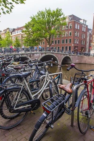 Amsterdam, Netherlands, on July 10, 2014. Bicycles are parked on the city street on the bank of the channel — Stock Photo, Image