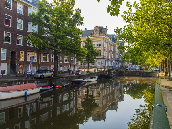 Amsterdam, Netherlands, on July 10, 2014. Typical urban view with old buildings on the bank of the channel and boats moored at bank — Stock Photo, Image