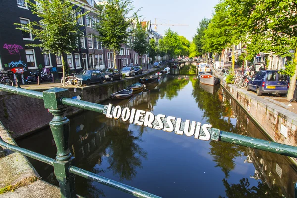 Amsterdam, Niederlande, am 10. Juli 2014. Typische Stadtansicht mit alten Gebäuden am Ufer des Kanals und Booten, die am Ufer festmachen — Stockfoto