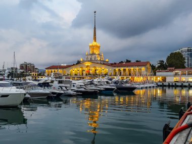 Sochi, Rusya, 18 Ekim 2021. Şehrin turistik sembollerinden biri olan deniz istasyonunun inşaatı, akşam ışıklarıyla Sochi Marina limanında yatlar.