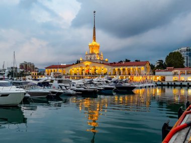 Sochi, Rusya, 18 Ekim 2021. Şehrin turistik sembollerinden biri olan deniz istasyonunun inşaatı, akşam ışıklarıyla Sochi Marina limanında yatlar.