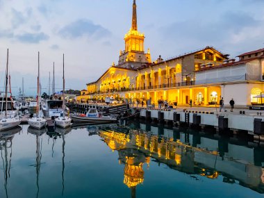 Sochi, Rusya, 18 Ekim 2021. Şehrin turistik sembollerinden biri olan deniz istasyonunun inşaatı, akşam ışıklarıyla Sochi Marina limanında yatlar.