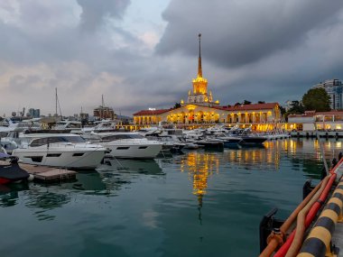 Sochi, Rusya, 18 Ekim 2021. Şehrin turistik sembollerinden biri olan deniz istasyonunun inşaatı, akşam ışıklarıyla Sochi Marina limanında yatlar.