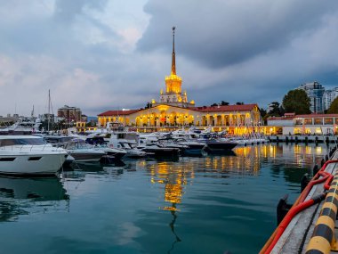 Sochi, Rusya, 18 Ekim 2021. Şehrin turistik sembollerinden biri olan deniz istasyonunun inşaatı, akşam ışıklarıyla Sochi Marina limanında yatlar.