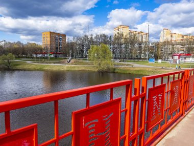 Pushkino, Rusya, 26 Nisan 2021. Serebryanka nehri kıyısındaki yeni çok katlı binalar ve nehir yoluyla yaya köprüsünden görüntüler