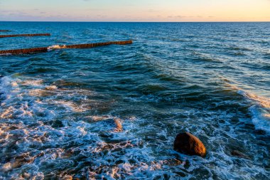 Deniz manzarası. Gün batımında dalgalar ve köpüklerle sörf yapmak. Doğa arkaplanı