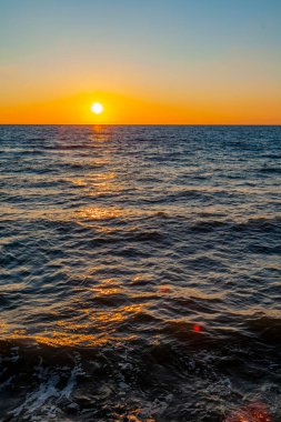Deniz manzarası. Gün batımında dalgalar ve köpüklerle sörf yapmak. Doğa arkaplanı