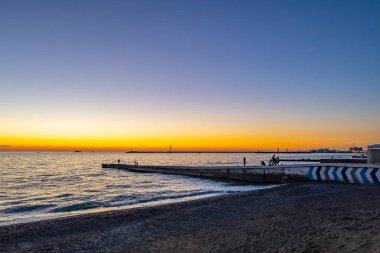 Sochi, Rusya, 20 Ekim 2021. Günbatımında Karadeniz kıyısındaki bir rıhtımda insanlar