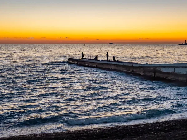 Sochi, Rusya, 20 Ekim 2021. Günbatımında Karadeniz kıyısındaki bir rıhtımda insanlar