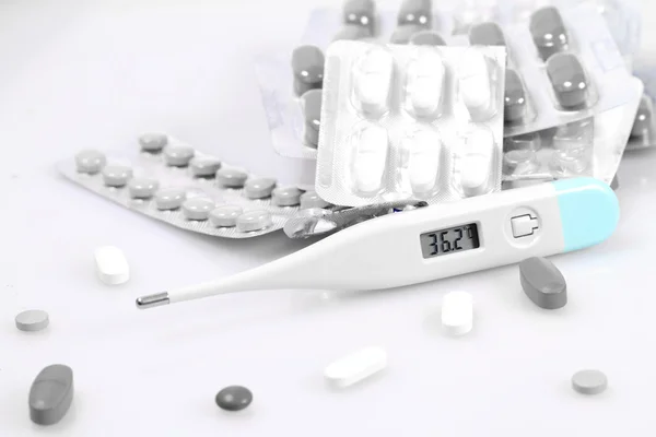 Białe tabletki i termometr — Zdjęcie stockowe