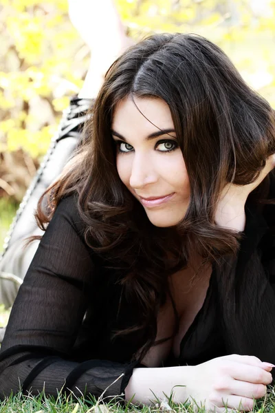 Beautiful young woman lies on green grass — Stock Photo, Image