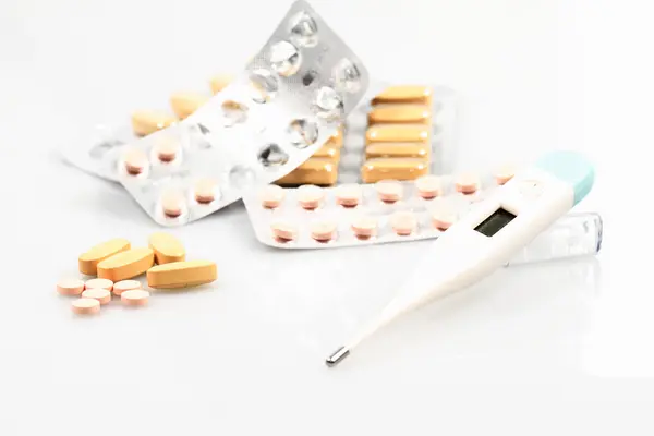 Białe tabletki i termometr — Zdjęcie stockowe