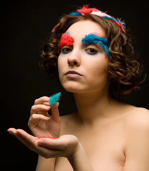 Girl holding colorful feathers — Stock Photo, Image