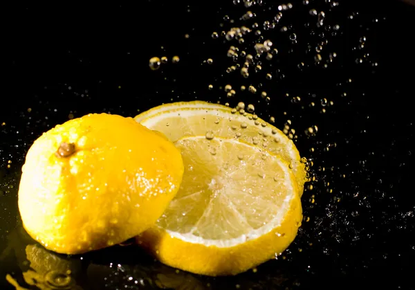 Sötét háttér, fröccsenő víz alatt vágott citrom — Stock Fotó