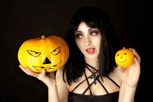 Mujer con maquillaje de Halloween sosteniendo una calabaza y una naranja —  Fotos de Stock