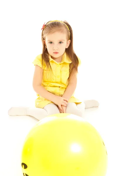 Pequeña niña enojada sentada en el suelo y mirando al globo —  Fotos de Stock