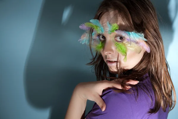 Girl with colorful feather on her face — Stock Photo, Image