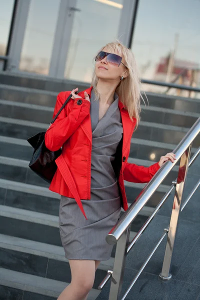 Frau in roter Jacke steht auf dem Geschäft Stockbild