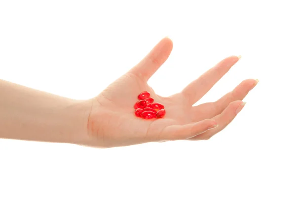 Женская рука с красными таблетками, изолированными на белом — стоковое фото