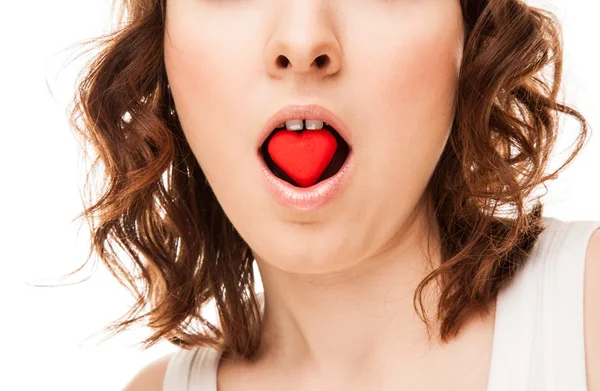 Jeune femme avec un cookie en forme de coeur dans la bouche — Photo