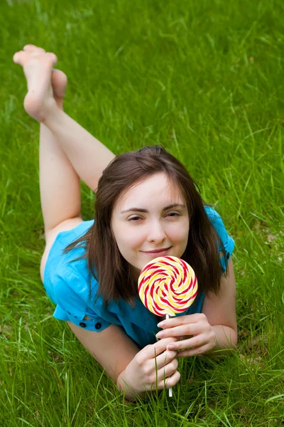 Bella donna con lecca-lecca sdraiata sull'erba — Foto Stock