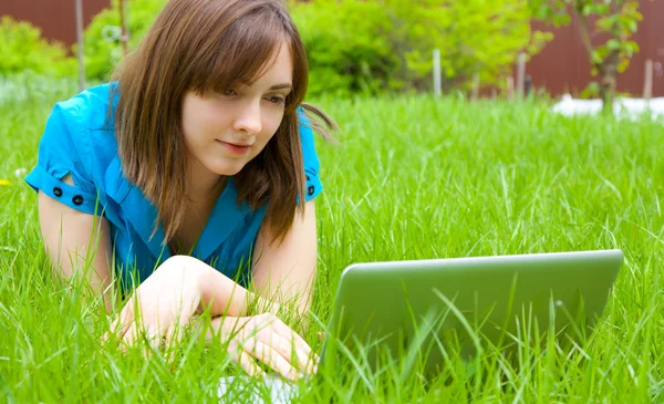 Женщина с ноутбуком лежит на траве — стоковое фото