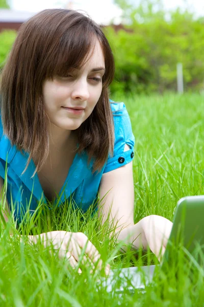 Жінка з ноутбуком лежить на траві — стокове фото