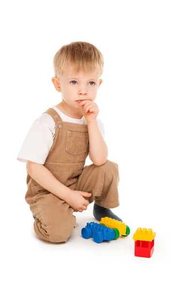 Задумчивый ребенок, играющий с изолированными игрушками — стоковое фото