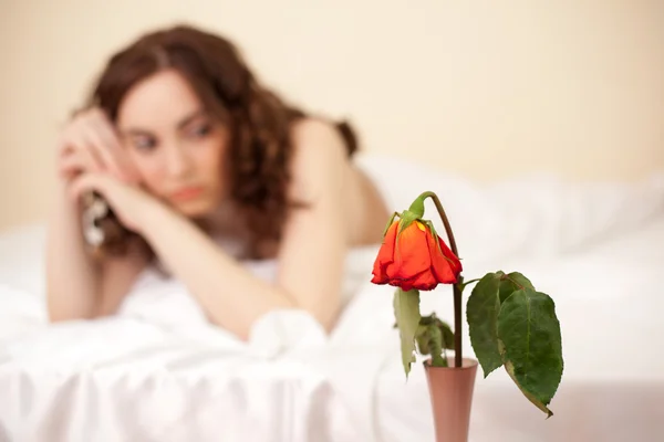 Γυναίκα στο κρεβάτι που ψάχνει για το τριαντάφυλλο (εστίαση στον τριαντάφυλλο) — Φωτογραφία Αρχείου