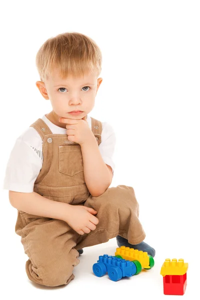 Niño pensativo jugando con juguetes aislados — Foto de Stock