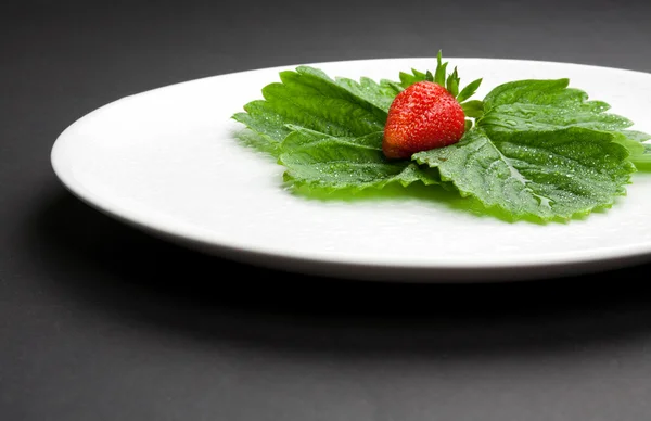 Erdbeere mit Blättern auf dem weißen Teller — Stockfoto