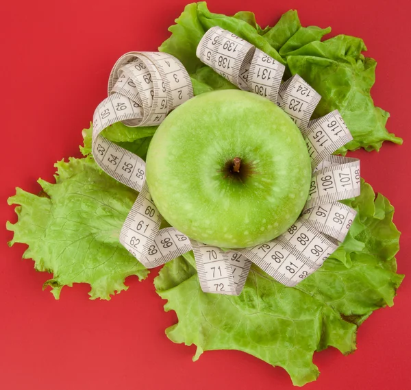 Picture of apple and tape measure on red — Stock Photo, Image