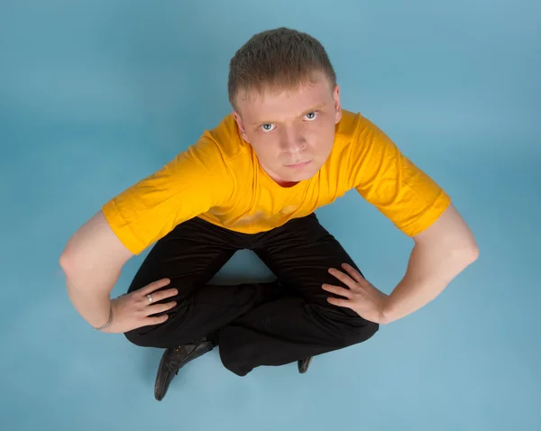 Young man sitting on the blue floor — Stock Photo, Image