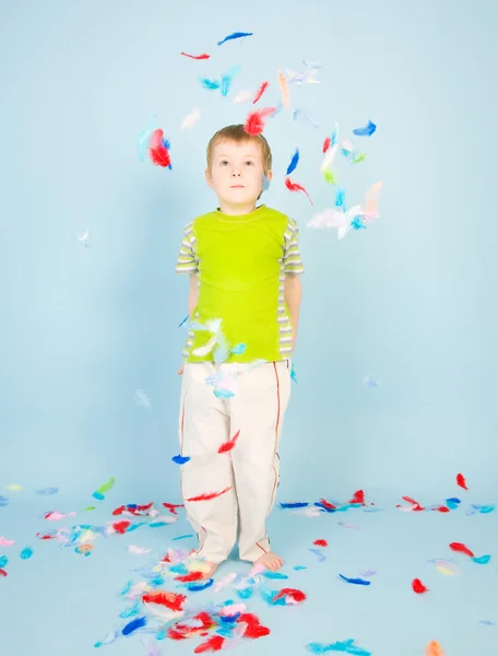 Menino brincando com um monte de penas — Fotografia de Stock