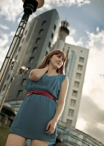 Beautiful woman in blue dress against building — Stock Photo, Image