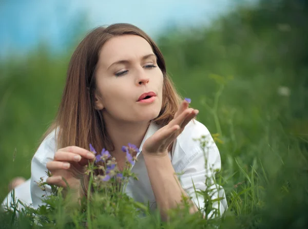 Frau mit Blumen auf dem Gras liegend — Stockfoto