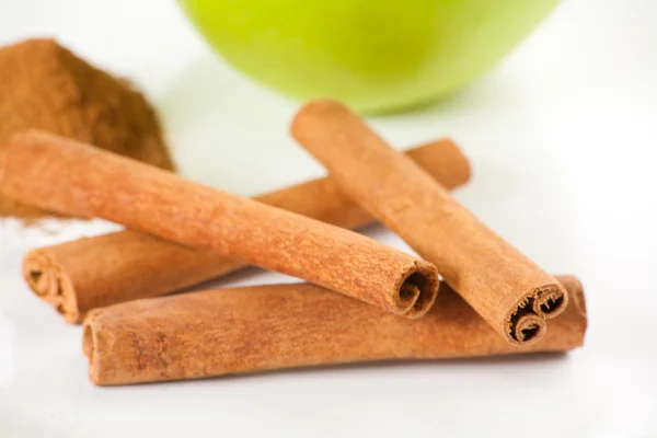 Green apple, cinnamon on white plate — Stock Photo, Image