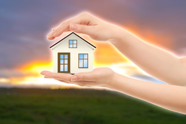 Picture of woman's hands holding a house against nature