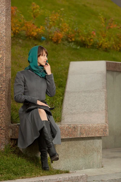 Hermosa mujer con estilo en abrigo gris sentado al aire libre —  Fotos de Stock