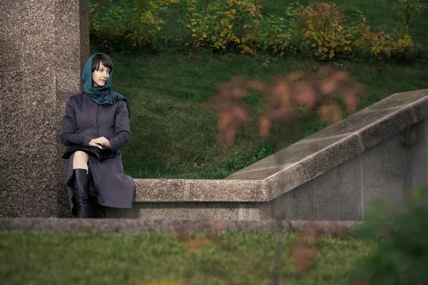 Beautiful stylish woman in grey coat sitting outdoors — Stock Photo, Image