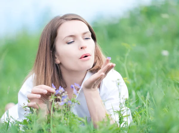 Žena s květy, ležící na trávě — Stock fotografie