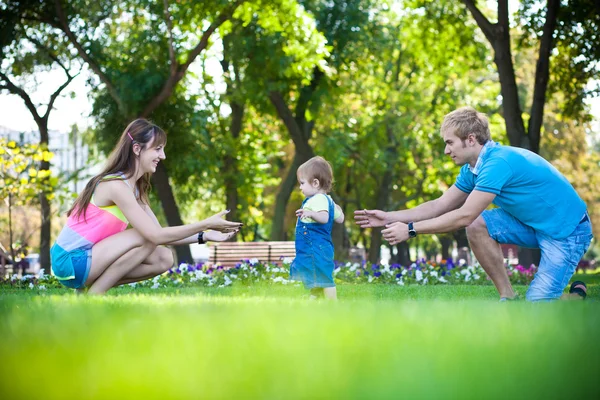 Padres felices con un bebé en un parque de verano verde —  Fotos de Stock