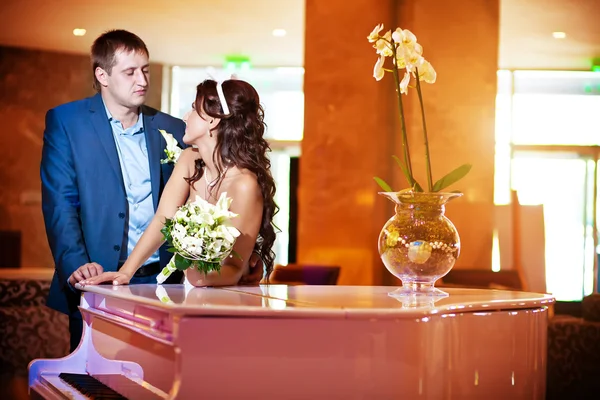 Happy bride and groom next to the piano — Stock Photo, Image